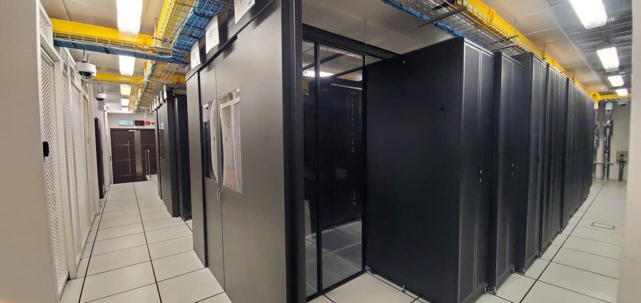 Clean white-floored server room corridor with black server cabinets in enterprise data center facility
