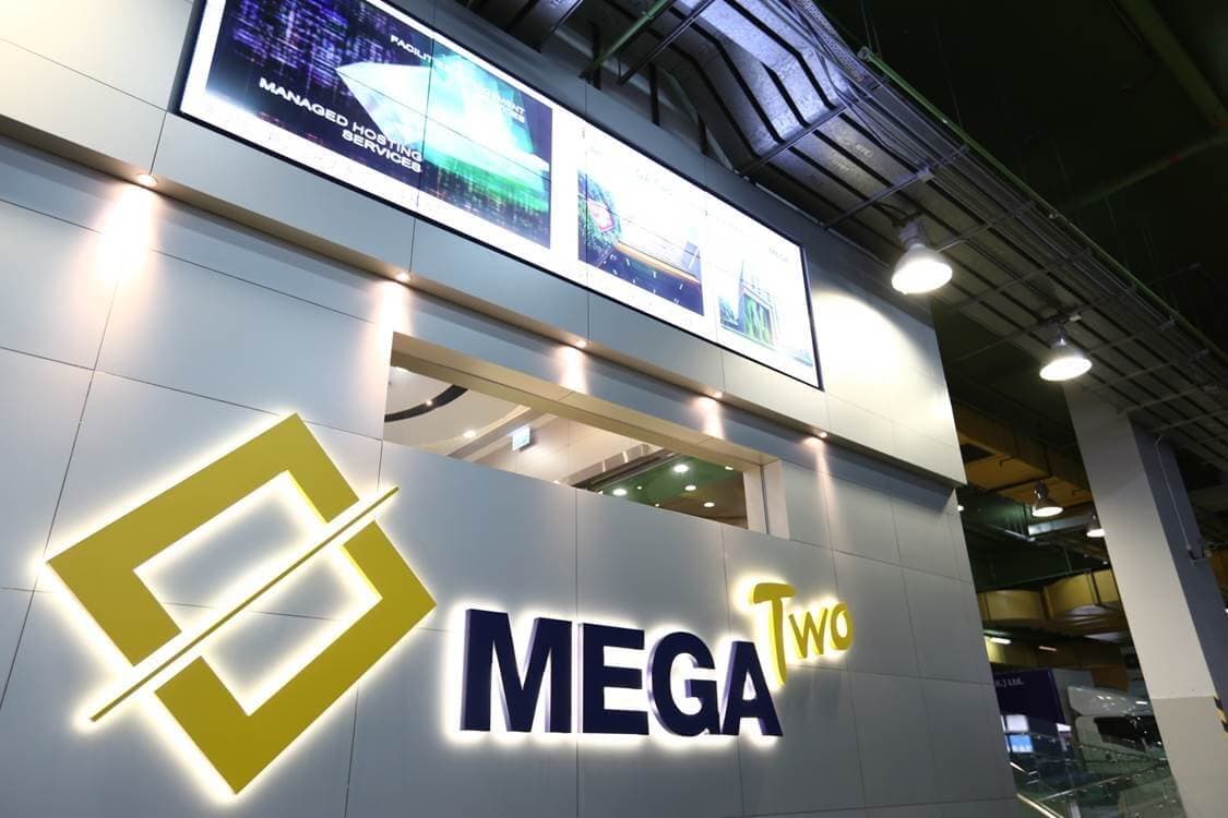 MEGA-Two data center entrance with illuminated logo, digital displays showing managed hosting services, and modern white paneled walls