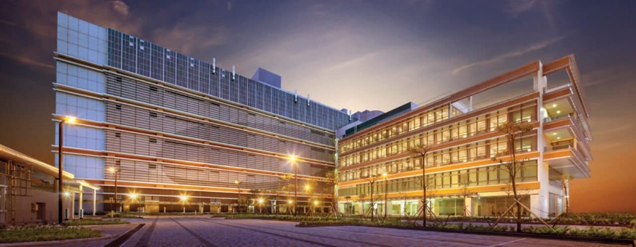 Modern data center campus with illuminated facade at dusk, featuring horizontal louvers and energy-efficient design with multiple buildings