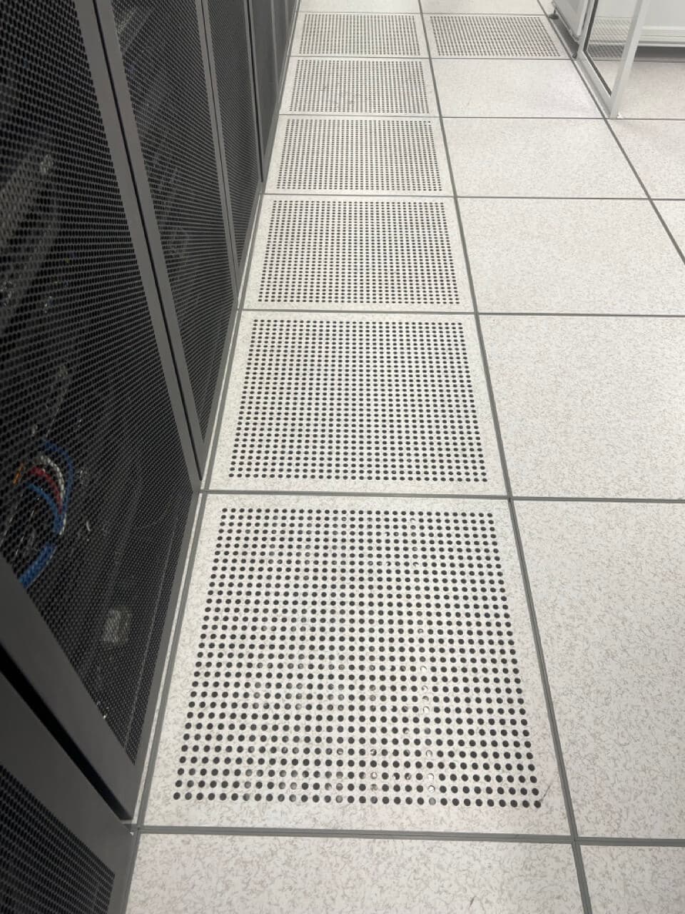 Climate-controlled data center environment with raised floor ventilation system for server cooling