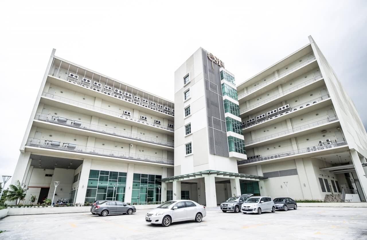 Modern white data center facility with multi-story building, glass atrium, and parking area