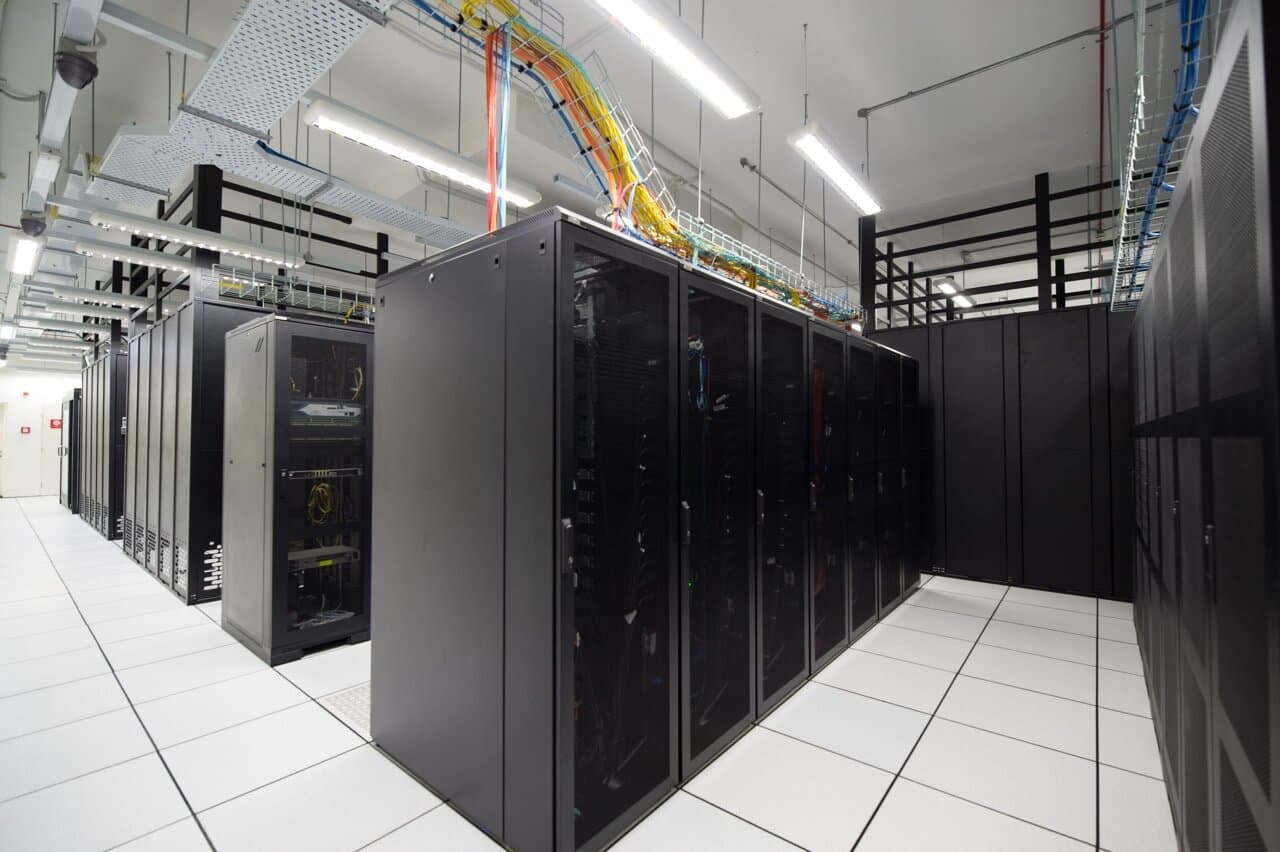 Professional server room with rows of black server cabinets and overhead cable management