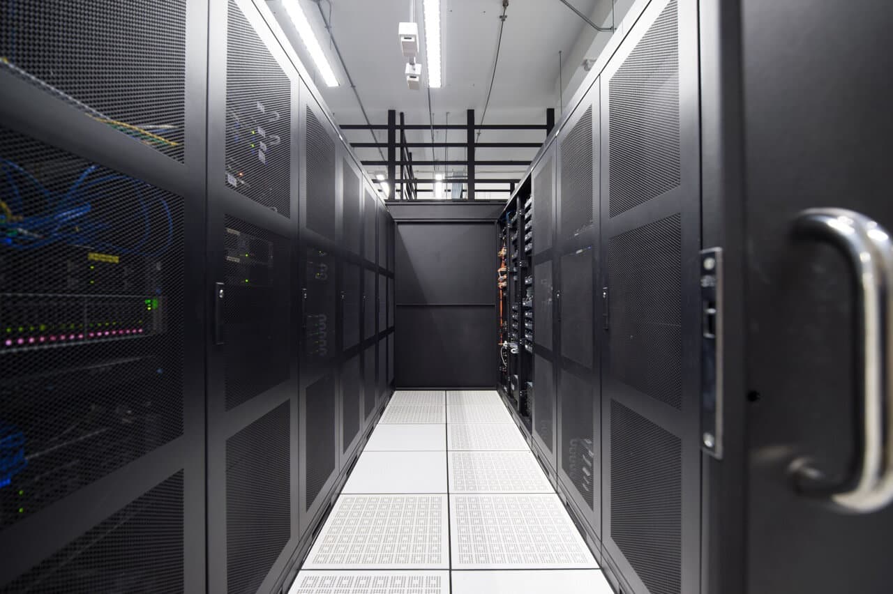 Server corridor with perforated floor tiles and organized rack arrangement for optimal airflow