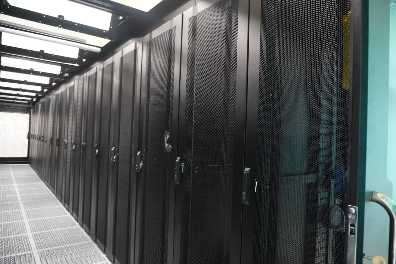 Side view of server rack corridor showing perforated doors and cable management systems