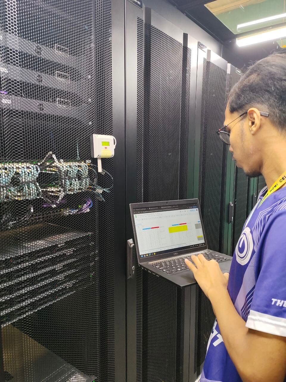 IT technician monitoring server equipment with laptop displaying diagnostic dashboard