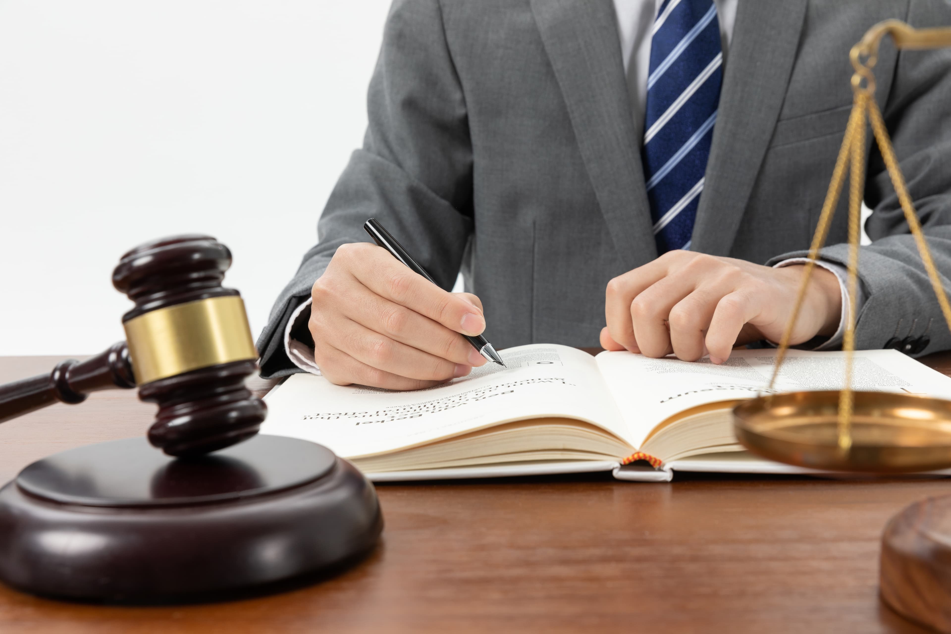 Lawyer writing a book on a table with a gavel in front.
