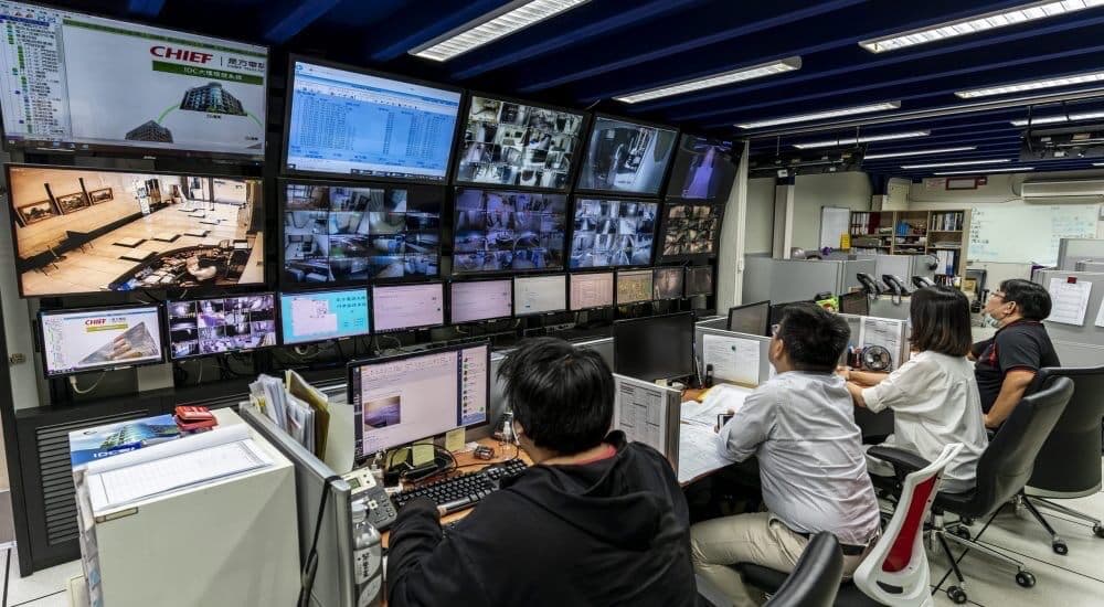 Network operations center with multiple staff monitoring live systems on display screens