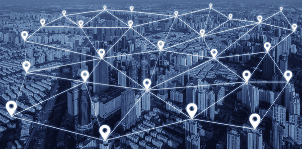 Aerial view of a city overlaid with a digital network. White location pins and connecting lines form a mesh, depicting connectivity and urban technology. Aerial view of a city overlaid with a digital network. White location pins and connecting lines form a mesh, depicting connectivity and urban technology.