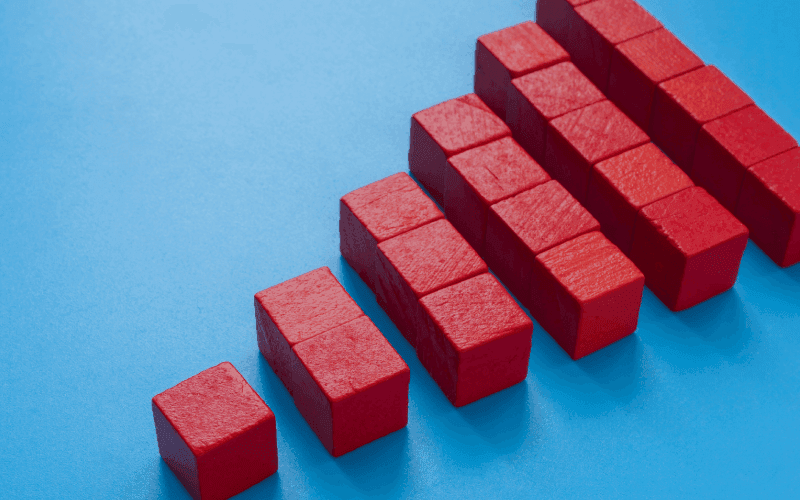 Red blocks arranged in ascending order on a blue background, forming a bar graph. The image conveys growth or progress. Red blocks arranged in ascending order on a blue background, forming a bar graph. The image conveys growth or progress.
