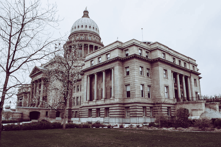 Grand stone building with a large domed roof and tall columns, surrounded by leafless trees and green lawn, under an overcast sky. Majestic and historical. Grand stone building with a large domed roof and tall columns, surrounded by leafless trees and green lawn, under an overcast sky. Majestic and historical.
