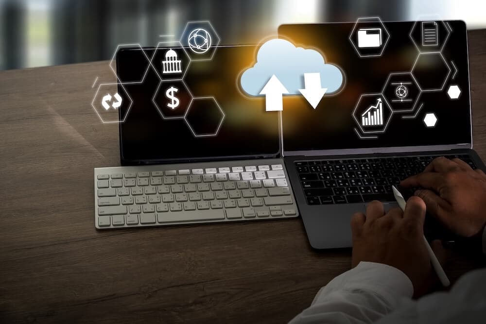 Hands typing on a laptop with a digital cloud icon and data symbols, symbolizing cloud computing. Hands typing on a laptop with a digital cloud icon and data symbols, symbolizing cloud computing.