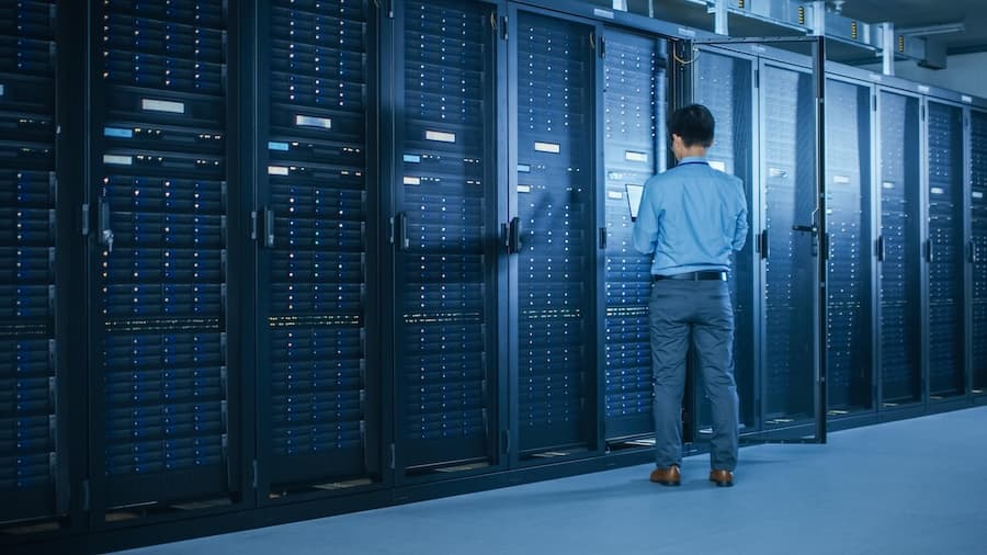 A technician inspecting server racks in a data center, symbolizing managed colocation services for secure server hosting. A technician inspecting server racks in a data center, symbolizing managed colocation services for secure server hosting.